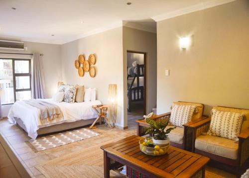 a bedroom with a bed and a living room with a table at Ponciana Superior Guesthouse in Hartbeespoort