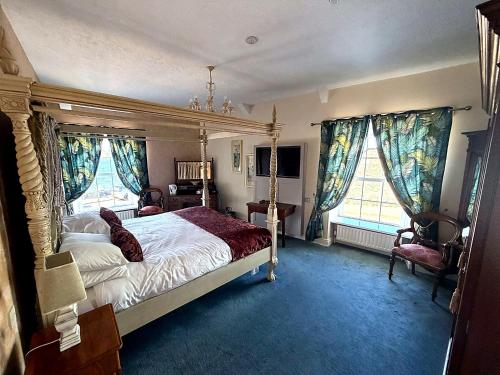 a bedroom with a canopy bed and two windows at The Portaferry Hotel in Portaferry
