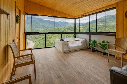 a room with a tub and some chairs and windows at Vaio Resort in Keda in K'eda