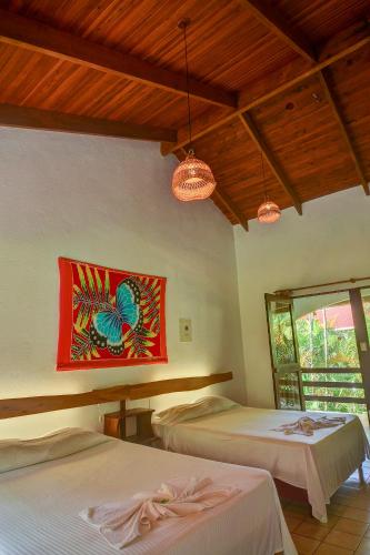 a bedroom with two beds and a painting on the wall at Hotel Pochote Grande in Jacó