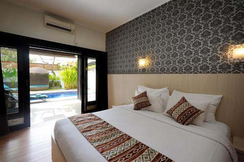 a bedroom with a large white bed and a window at The Nakula Villas in Legian