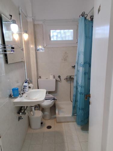 a bathroom with a sink and a toilet and a window at Maritsas Apartments in Roda