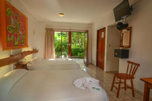 a hotel room with two beds and a television at Hotel Pochote Grande in Jacó