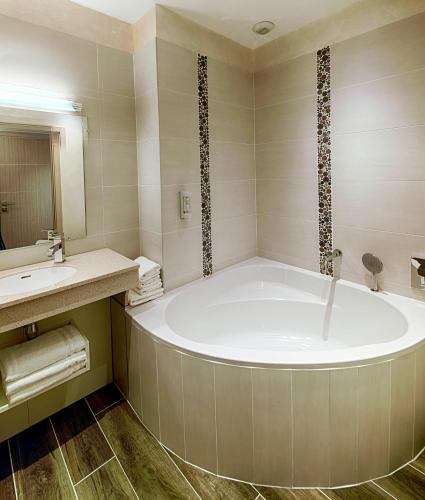 a bathroom with a tub and a sink at LE VAL MORET Hôtel Restaurant et Spa in Magnant