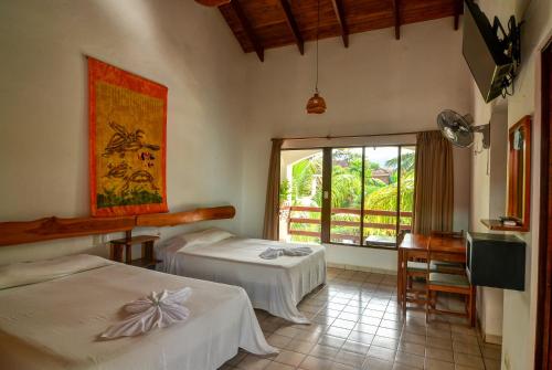 a room with two beds and a large window at Hotel Pochote Grande in Jacó