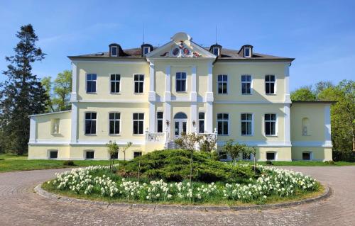 a large white house with flowers in front of it at Schloss Schmuggerow in Schmuggerow
