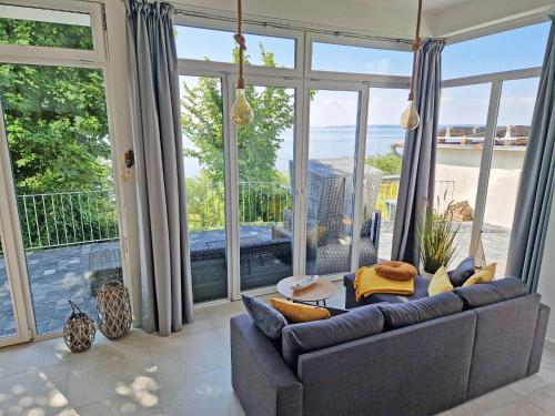 a living room with a couch and large windows at Villa Küstenperle, Meerblick-Appartements in Sassnitz