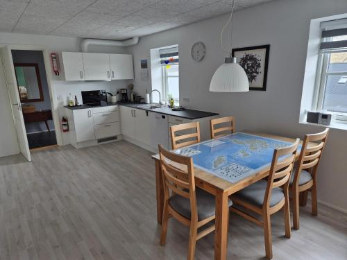 a kitchen and dining room with a table and chairs at Cosy apartment in Norðskála in Norðskáli