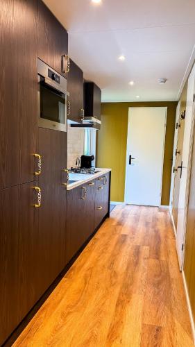 a kitchen with wooden flooring and a kitchen with a stove at Panterhuis Leo l Tiny House l Buitenbad, airco, speeltuin, bostuin in Epe