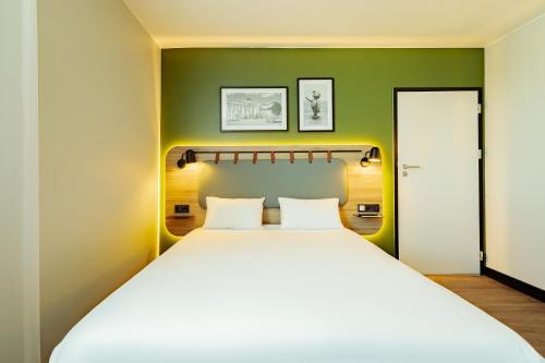 a bedroom with a large white bed with a green wall at Campanile PRIME - Lodz in Łódź