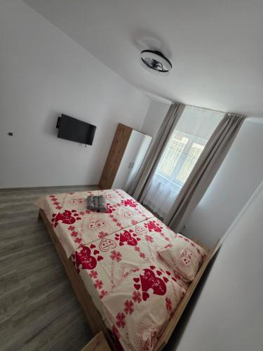 a bedroom with a bed with a red and white blanket at Ionela in Năvodari