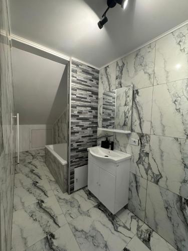 a bathroom with a sink and a tub and marble walls at Ionela in Năvodari
