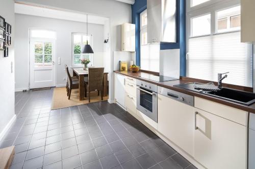 a kitchen with white cabinets and a table with chairs at Rothen Huus in Norderney