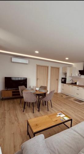 a living room with a table and chairs and a kitchen at Theodora Apartman in Zánka