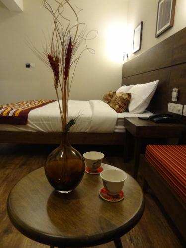 a room with a table with two cups and a vase at Utse Suites in Bengaluru