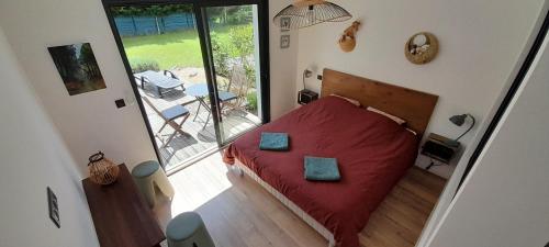 a bedroom with a red bed and a balcony at Maison GINKGO in Hourtin
