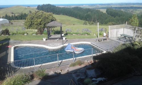 une grande piscine avec un kiosque et un gonflable dans l'établissement Warwick Hills Rural Bed & Breakfast, à Papamoa