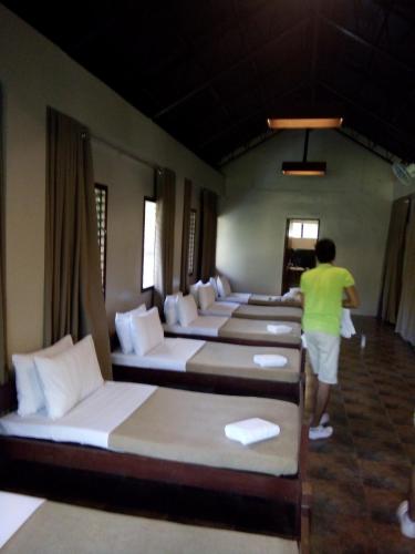 a man standing in a room with a row of beds at Sheridan Organic Farm and Resort in Maratapi