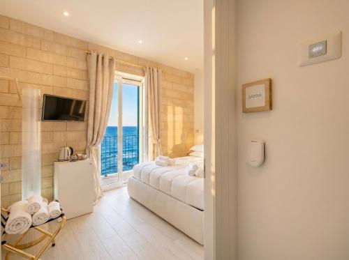 a bedroom with a bed and a large window at Terra | 2-Bedroom with Shared Kitchen & Balcony – Seafront Location in Polignano a Mare