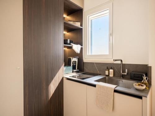 a small kitchen with a sink and a window at Terra | 2-Bedroom with Shared Kitchen & Balcony – Seafront Location in Polignano a Mare