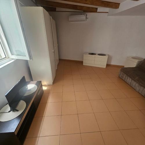 an empty room with a tiled floor and a kitchen at Apartman Stepanović 2 in Prijevor