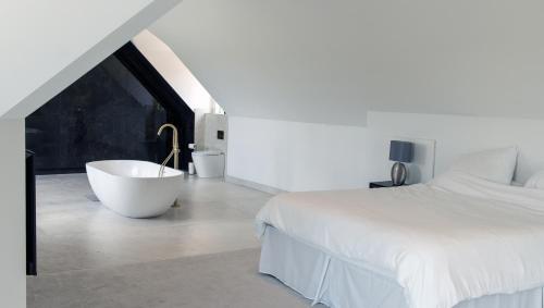 a white bedroom with a bath tub next to a bed at The Clock House in Sacomb