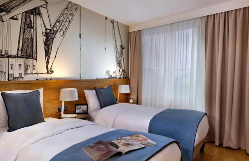 a hotel room with two beds and a window at Citadines Michel Hamburg in Hamburg