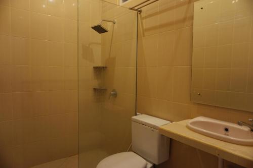 a bathroom with a shower and a toilet and a sink at Sari Indah Cottages in Kuta