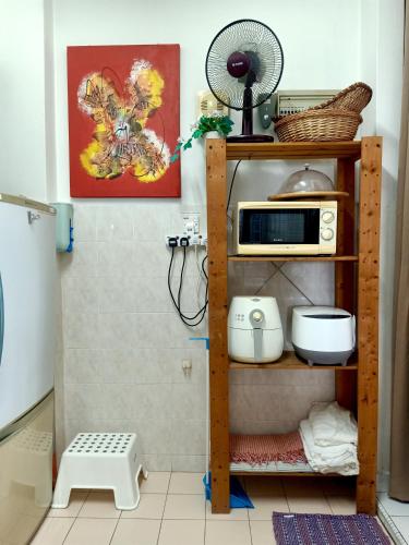 a kitchen with a shelf with a microwave and a fan at Cozy Master Room at Suria Kipark Damansara Apartment Homestay Sleeps 3 with Fully Equipped Kitchen and Laundry in Kepong