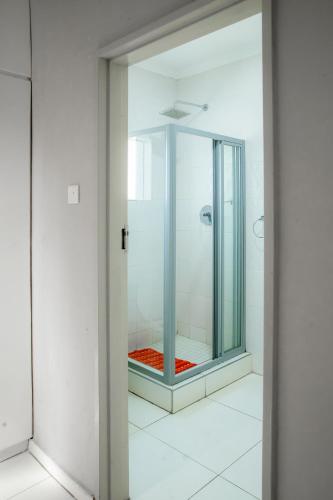 a bathroom with a shower with a glass door at Kentucky Hotel in Harare