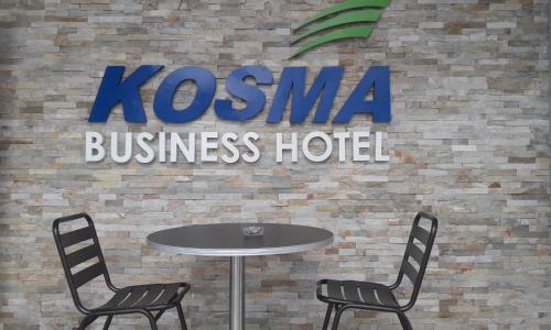 a table and two chairs in front of a hotel sign at Kosma Business Hotel in Kuantan