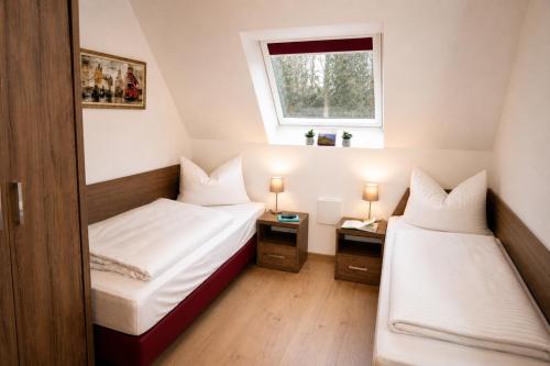 two beds in a small room with a window at Gästehaus Munk in Günzburg