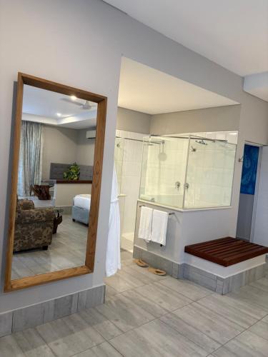 ein Badezimmer mit Dusche und Spiegel und ein Schlafzimmer in der Unterkunft Ecolux in Marracuene