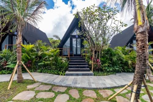 a house with a black roof and some palm trees at Anandinii Resort Sidemen by AGATA in Sidemen