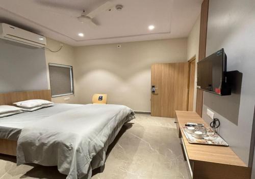 a bedroom with a bed and a table and a tv at Hotel Arunodaya Avenue in Srīkākulam