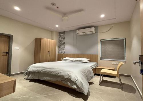 a bedroom with a bed and a desk and a tv at Hotel Arunodaya Avenue in Srīkākulam