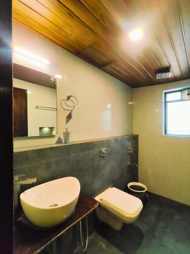 a bathroom with a sink and a toilet and a mirror at Fortune Resort in Alībāg