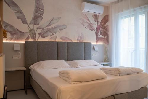 a bedroom with a large bed with white sheets at Hotel Nederland in Caorle