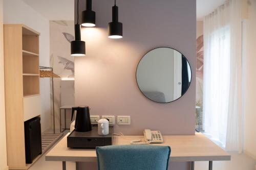 a room with a desk with a mirror and a phone at Hotel Nederland in Caorle