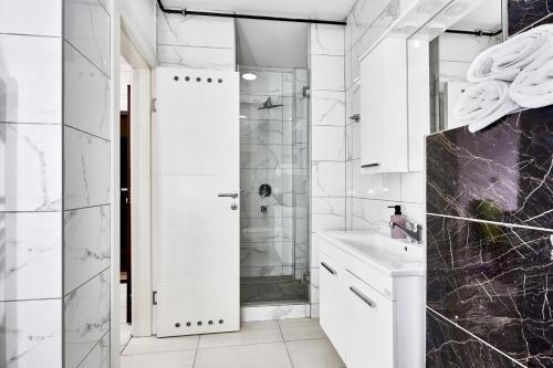 a white bathroom with a shower and a sink at Regency Aparthotel Sarajevo in Sarajevo