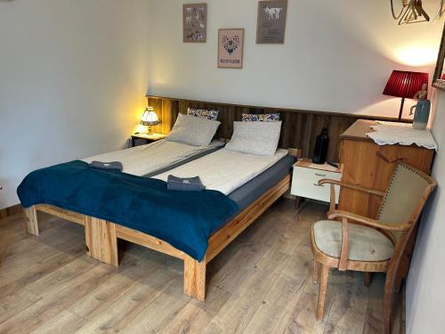 a bedroom with a bed with a chair and a desk at Apartamenty Cichy Kącik in Szymbark
