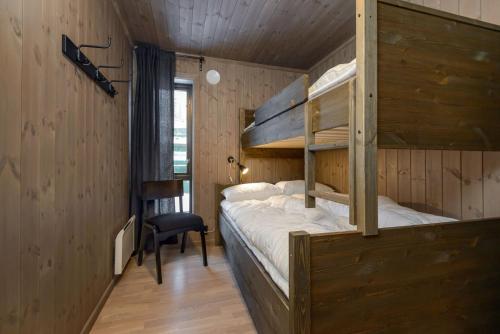 a bedroom with two bunk beds and a chair at Hytter og leiligheter i Kvitfjell - Alpinco in Ringebu