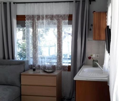 a kitchen with a sink and a window with curtains at A. & C. Michailidi (Haris Mihailidis) in Neos Marmaras