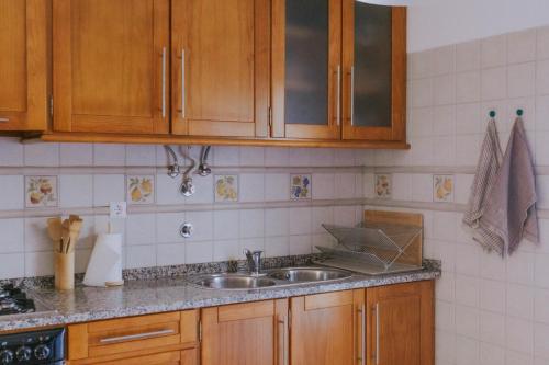 a kitchen with wooden cabinets and a sink at Casa do Mar - Almograve - Magnífico terraço com vista para o campo in Almograve