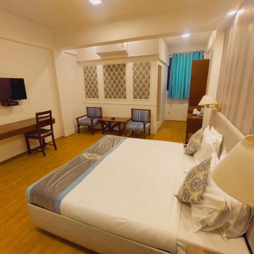 a bedroom with a large bed and a table and chairs at Hotel Samrat - A Boutique Hotel in Prayagraj