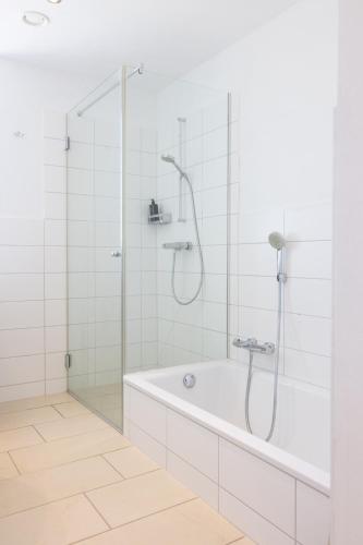 a white bathroom with a shower and a tub at Gasthof Leindl in Krems an der Donau
