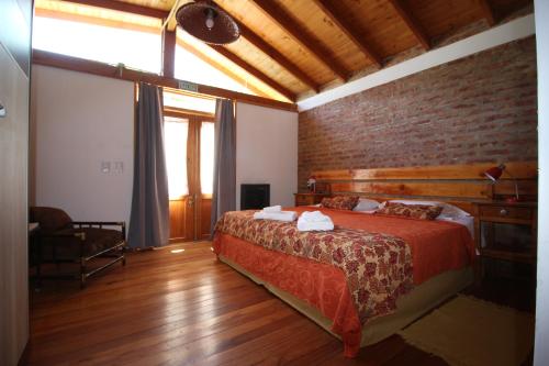 a bedroom with a bed and a brick wall at Cabaña Accesible Ipua in Lago Puelo