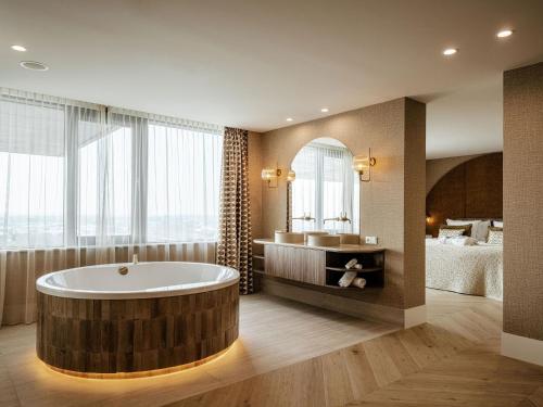 a bathroom with a large tub and a bedroom at Van der Valk Hotel Dordrecht in Dordrecht