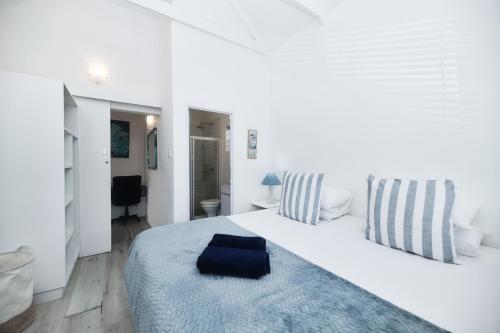 a white bedroom with a large white bed with a blue blanket at Owlet Cottage in Arniston in Arniston