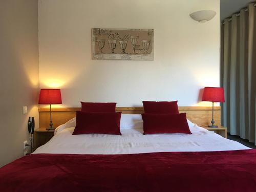 a bedroom with a bed with red pillows and two lamps at Le Clos Nicolas in Eugénie-les-Bains